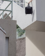 black square leather backpack hanging on stairs
