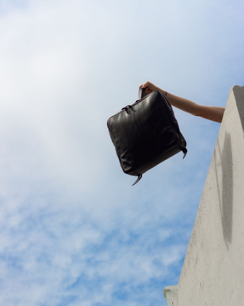 black square leather backpack with blue sky