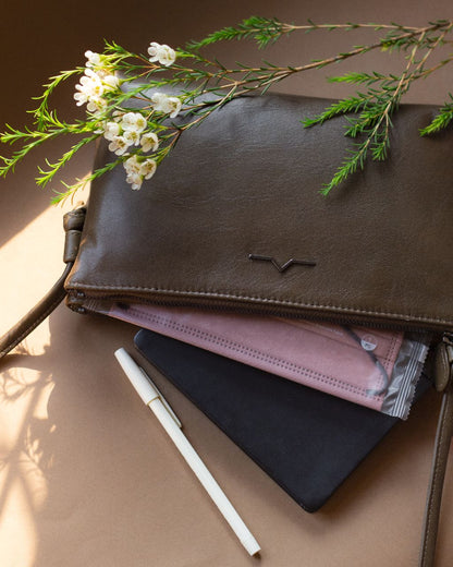 double zip rectangular crossbody in leather with face mask , note book and ball pens under natural lights