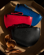 half moon mini leather pouch in 3 colour: blue, red and black with sun-dried orange slide in Christmas vibes close up