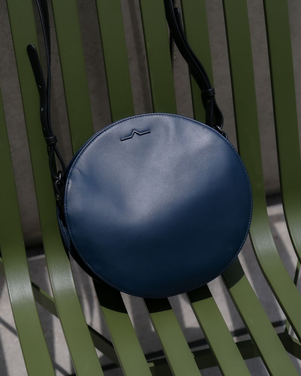 dark blue leather bag on green chair