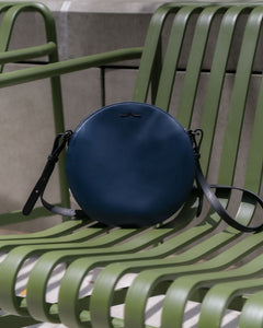 navy circle leather bag on green chair