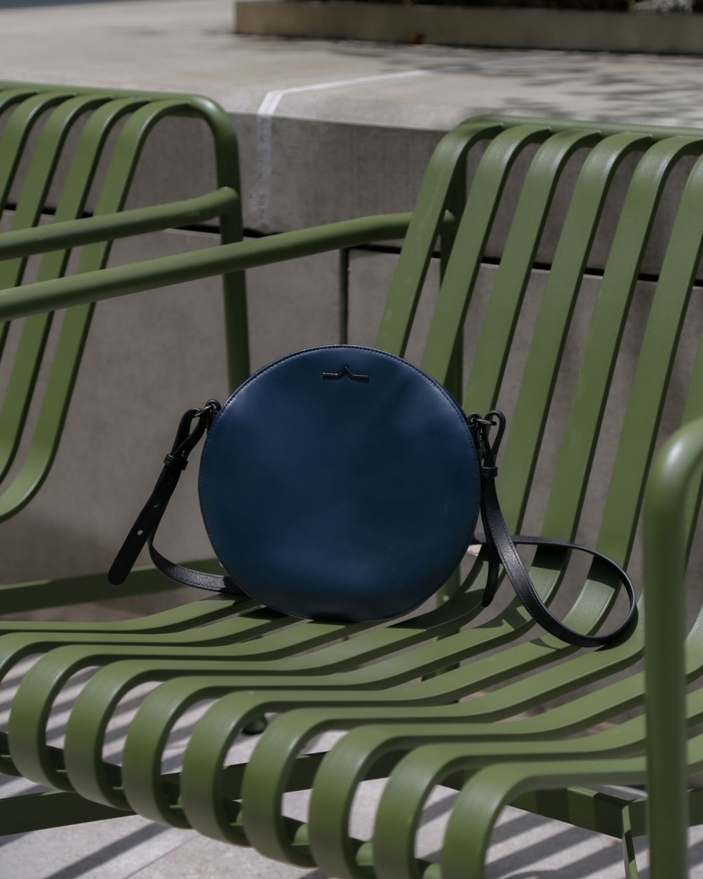 navy circle leather bag on green metal chair