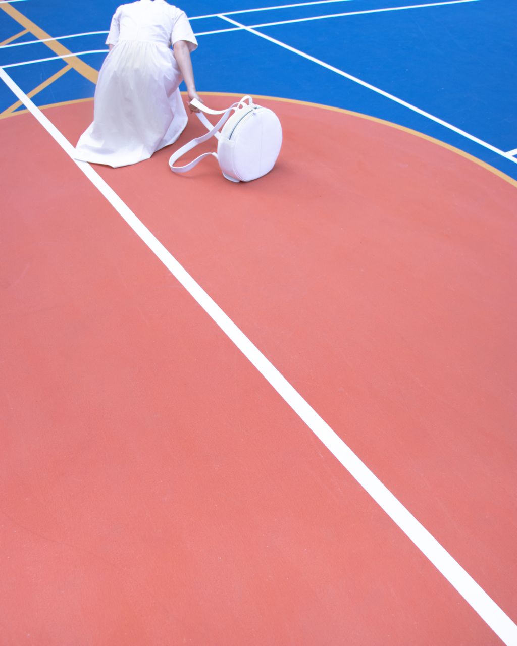 a girl holding a white leather circle backpack